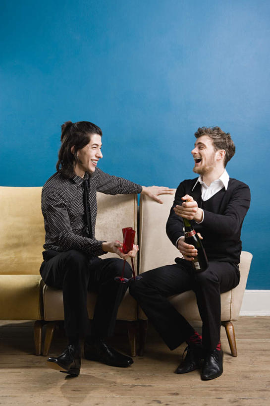 葡萄酒,西方人,两个人,伙伴,朋友,客厅,坐,笑,微笑,露齿笑,竖图,室内,白天,正面,奢侈,快乐,友谊,沙发,欧洲,欧洲人,蓝色背景,服装,墙,晃动,浪漫,注视,休闲装,墙壁,墙面,玻璃制品,酒,酒瓶,饮料,一个,衣服,蓝色,玻璃瓶,瓶子,香槟,观察,看,休闲,休闲服,诱惑,服饰,单个,观看,察看,起居室,关注,摇晃,布艺沙发,晃悠,气泡酒,起泡酒,汽酒,客堂,友情,男人,男性,年轻男性,白种人,坐着,彩图,全身,高兴,欢笑